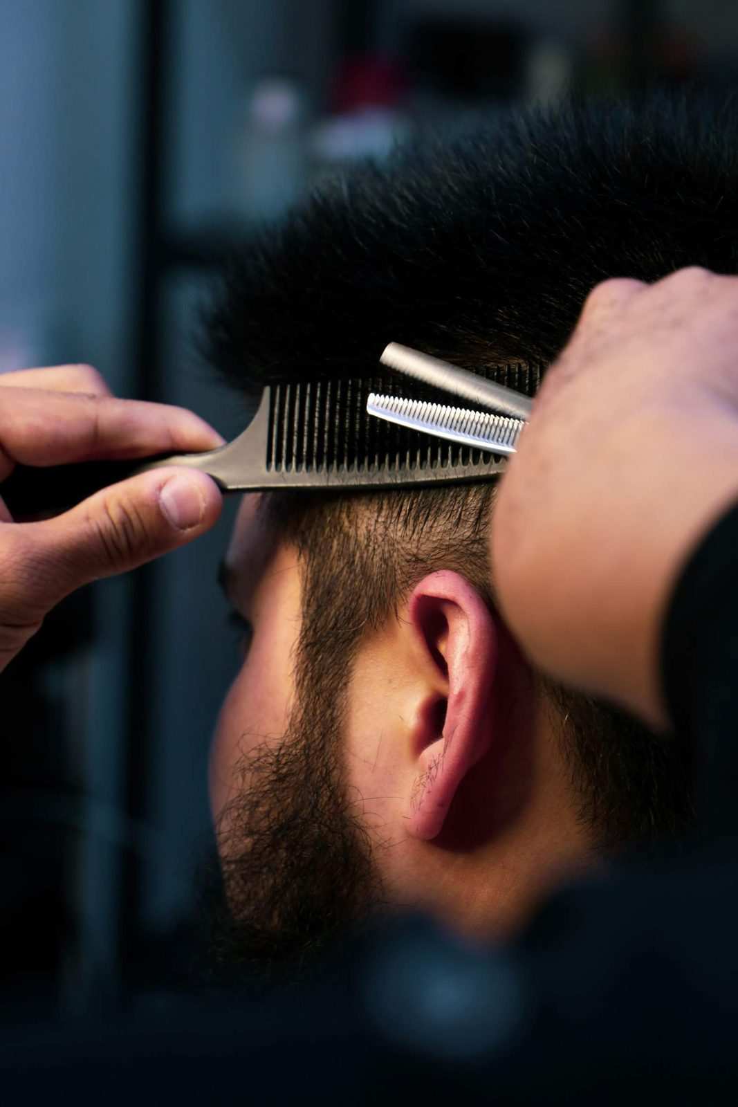 Barbero entresacando el cabello con tijera y peine